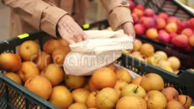 女人在超市买水果，黄色漂亮的苹果。 她把袋子放在可重复使用的袋子里。 生态包装，零